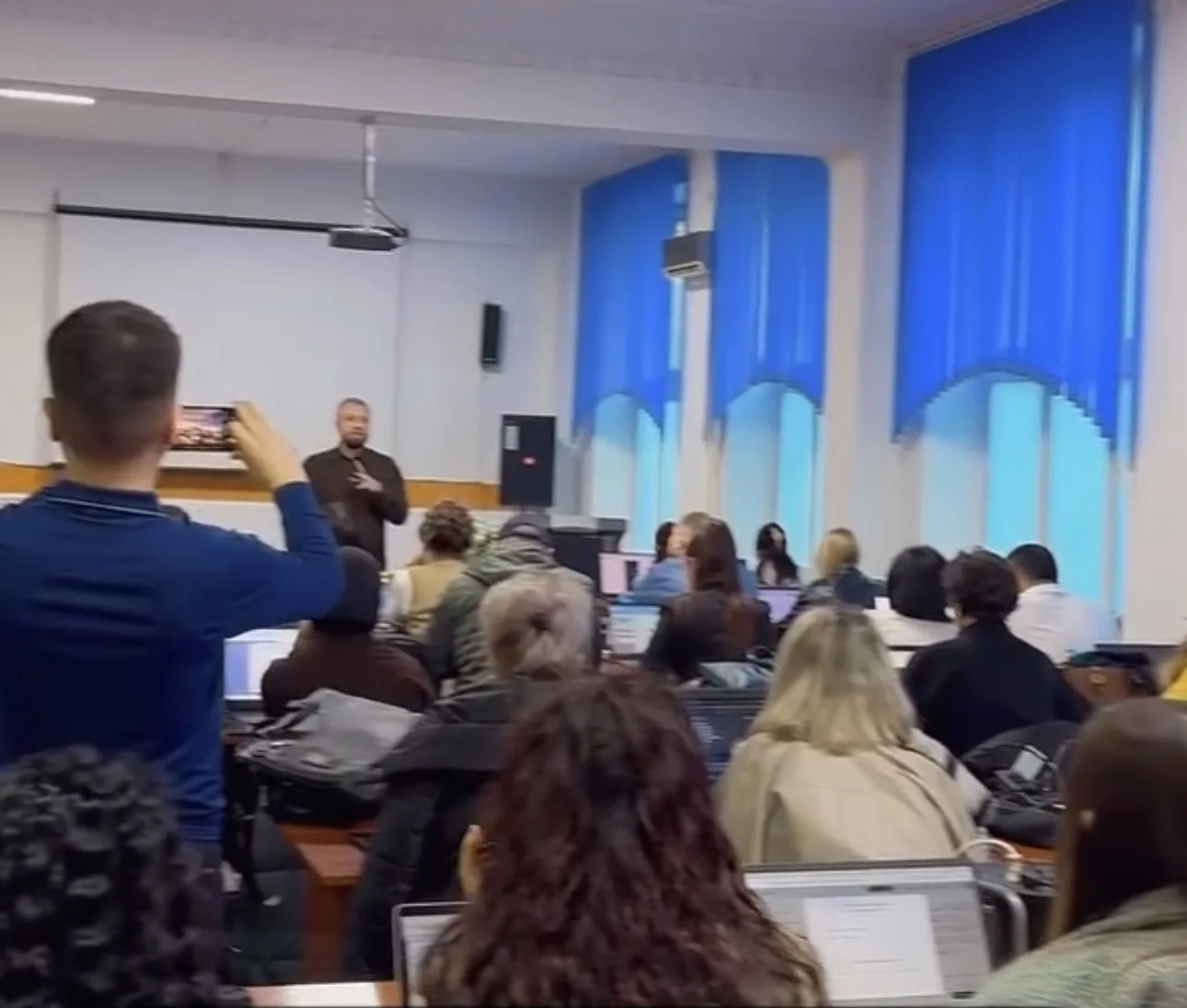 Участники работают за ноутбуками, один снимает экран на телефон